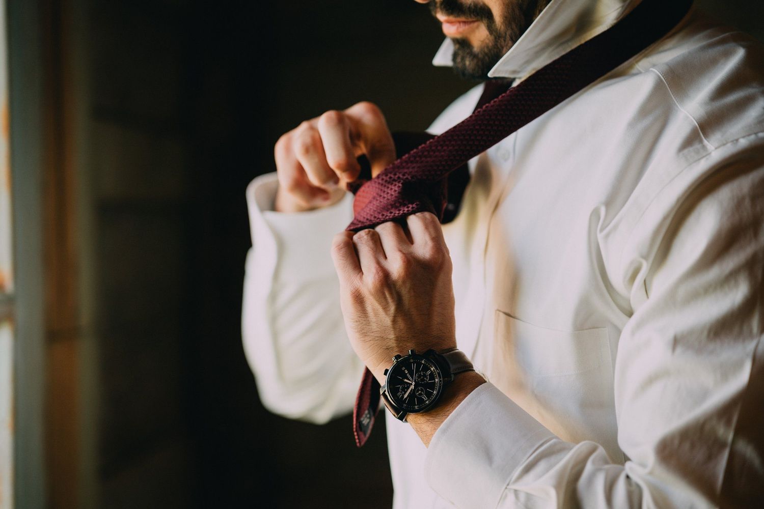 Close-up of formal attire details including bow tie and watch being adjusted.