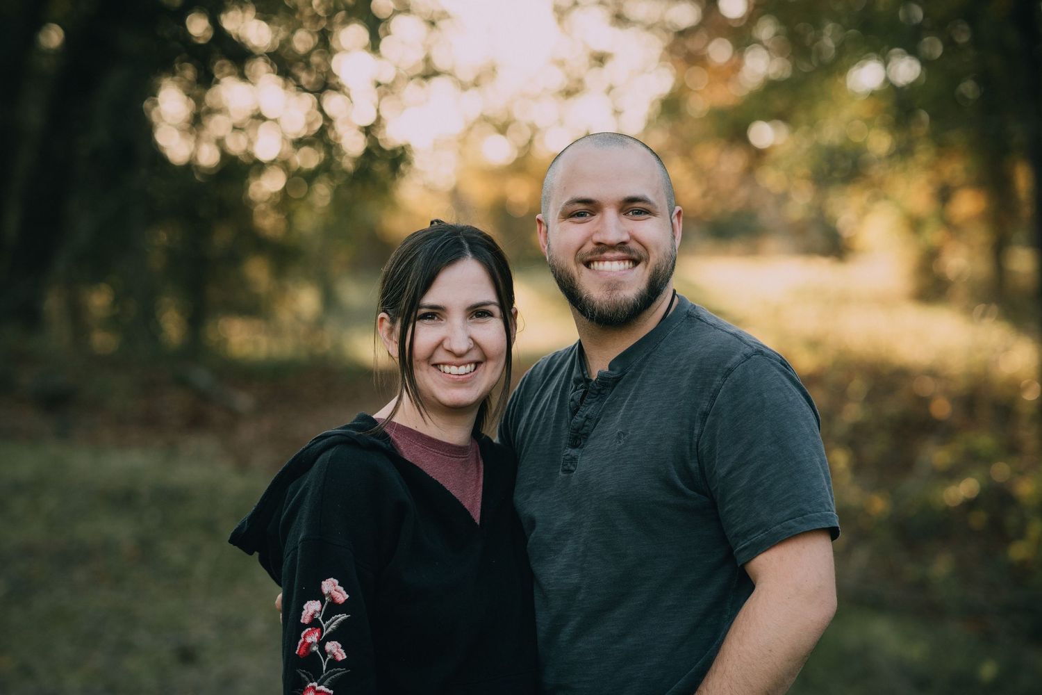 Outdoor family portrait session during golden hour with autumn trees in background.