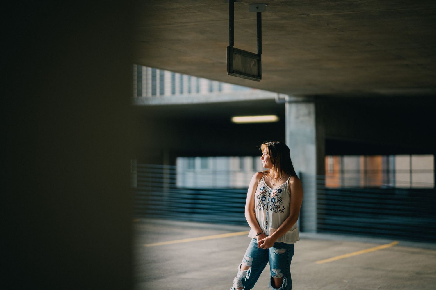 Dark concrete parking structure interior with dramatic lighting and shadows.