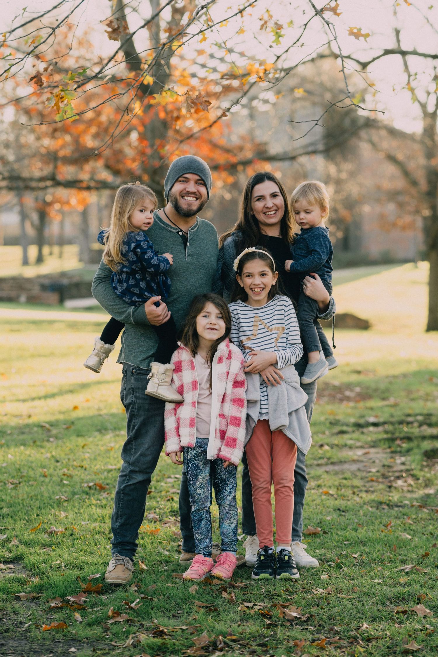 Group photo on autumn grass with fall foliage in background.