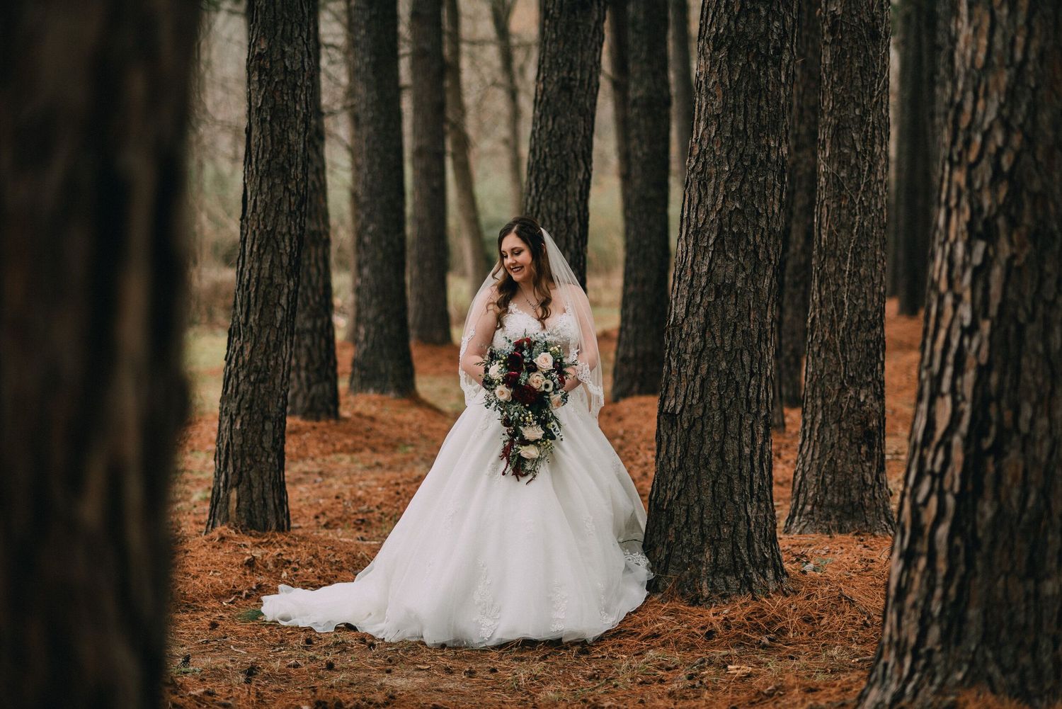 Wedding photography session in autumn forest with fallen pine needles.