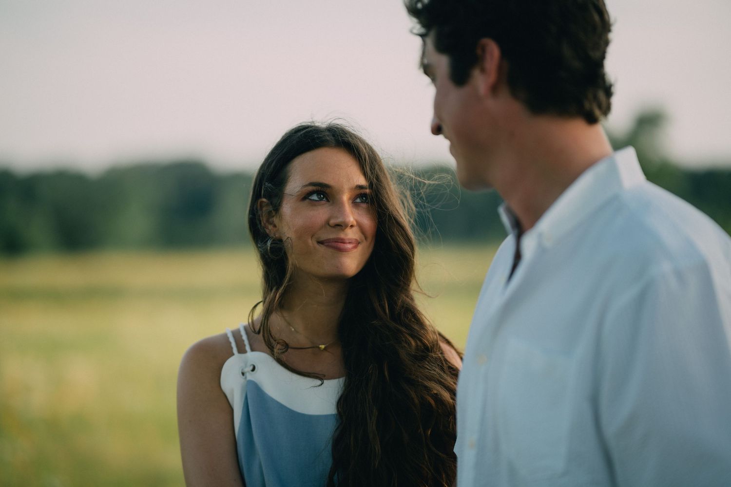 A romantic outdoor couple portrait with soft natural lighting in a field.