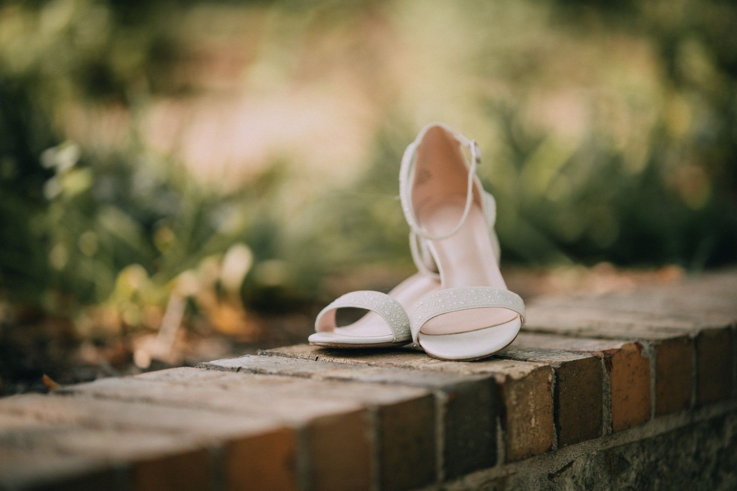 Wedding shoes placed on rustic wooden surface in natural outdoor setting.