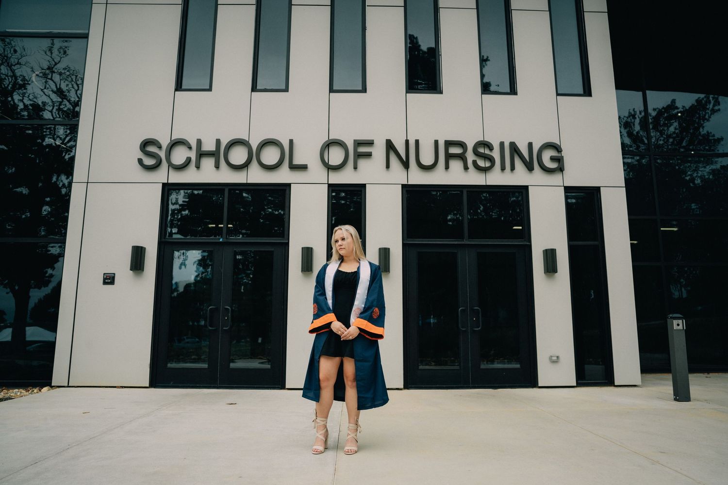 Modern school of nursing building exterior with white facade and glass windows.