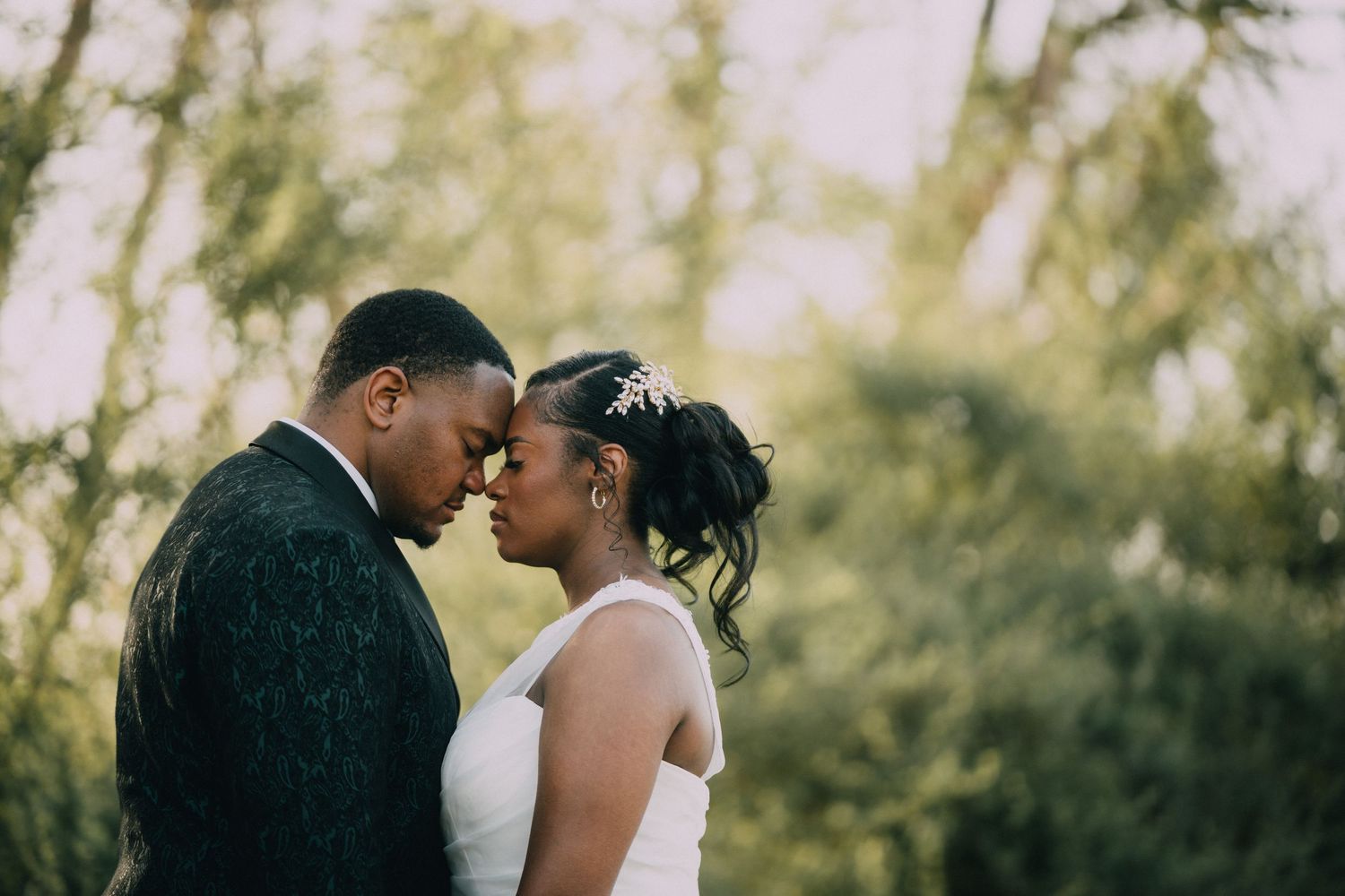 A tender moment between newlyweds in an outdoor setting.