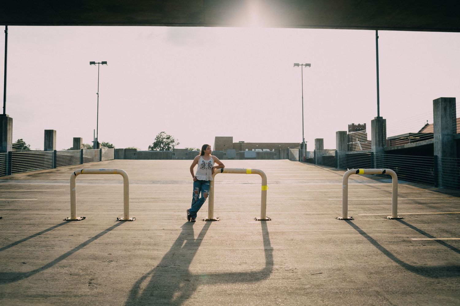 Empty parking lot with light poles casting long shadows across concrete surface.