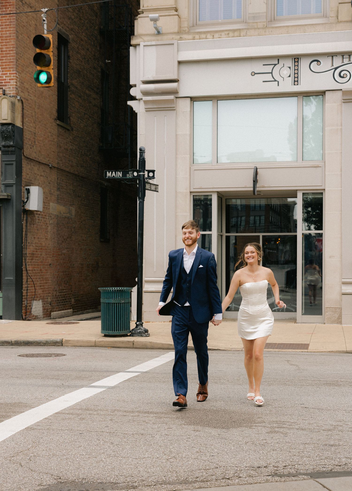 Happy couple holding hands while crossing a street intersection in downtown area.