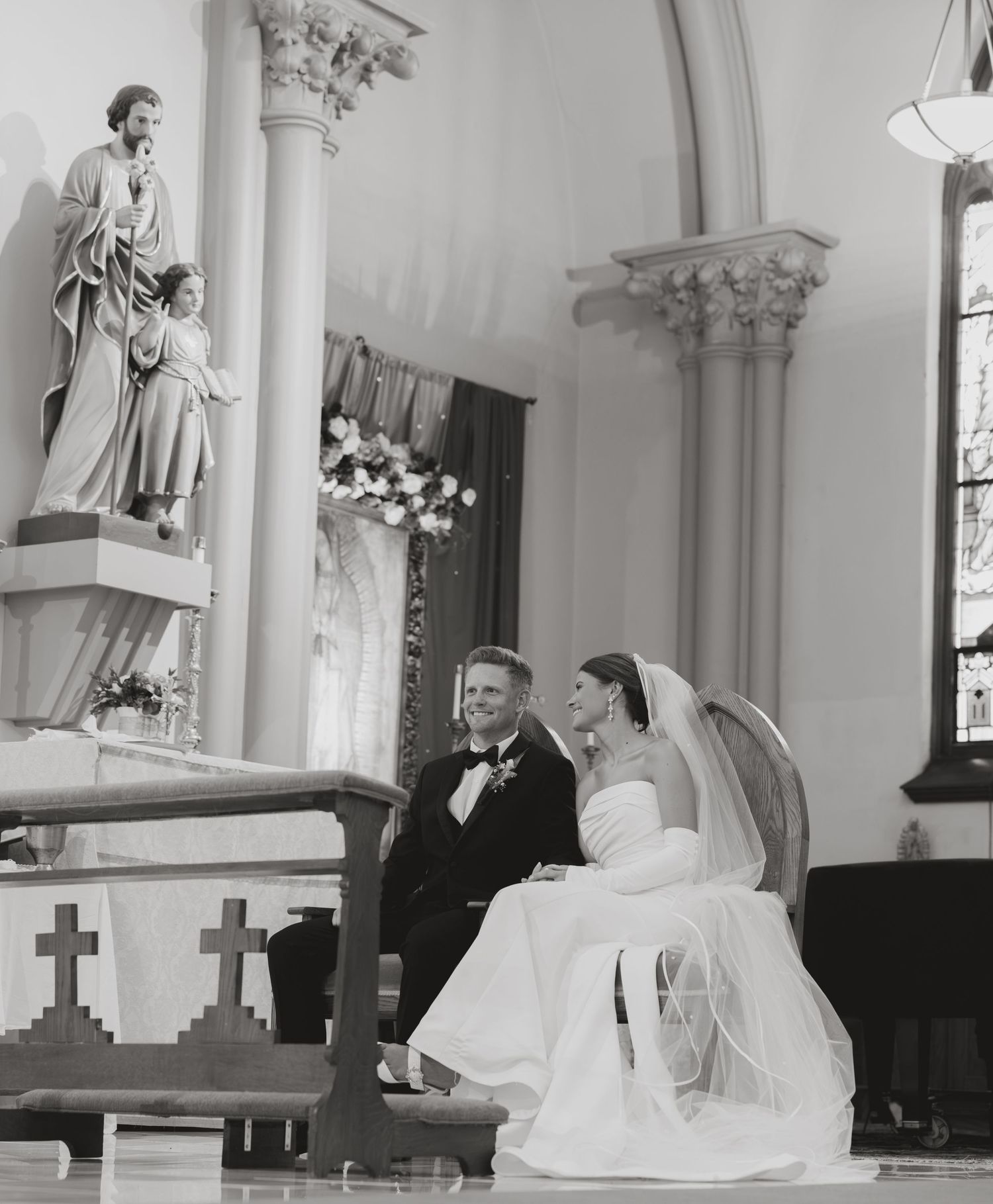 Black and white photo of bride and groom sharing a joyful moment at church altar.