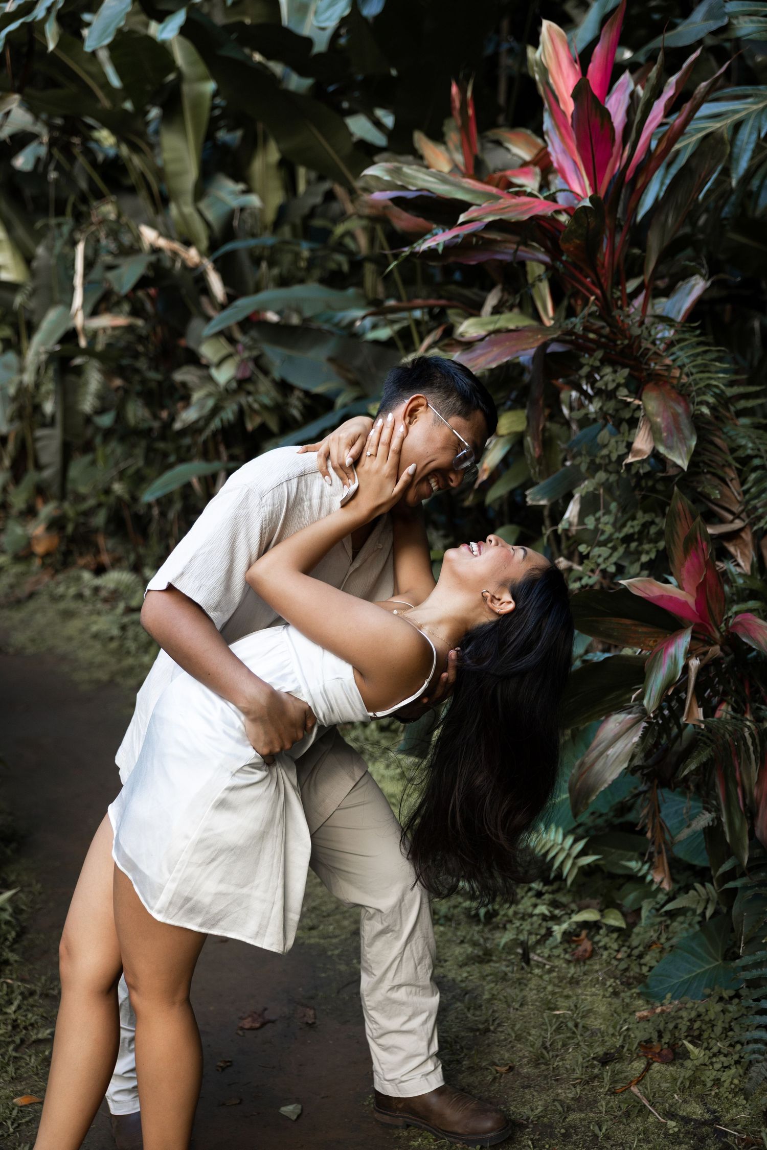 A romantic dip pose captured in a lush tropical garden setting.
