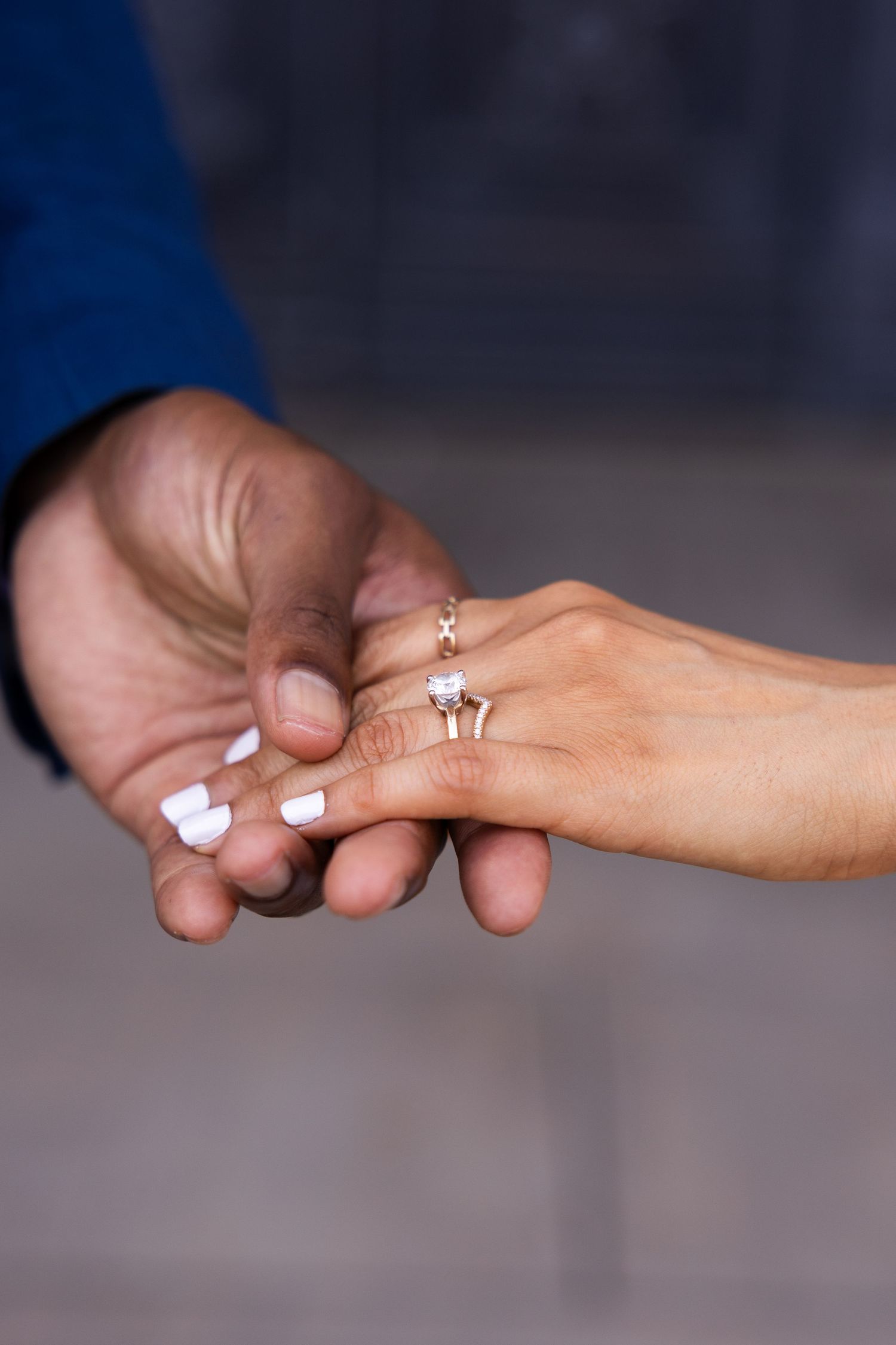 Close-up of hands with white nail polish and engagement rings showing a tender moment.