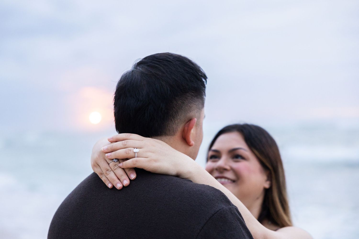 A couple embraces during a romantic sunset beach engagement photo session.