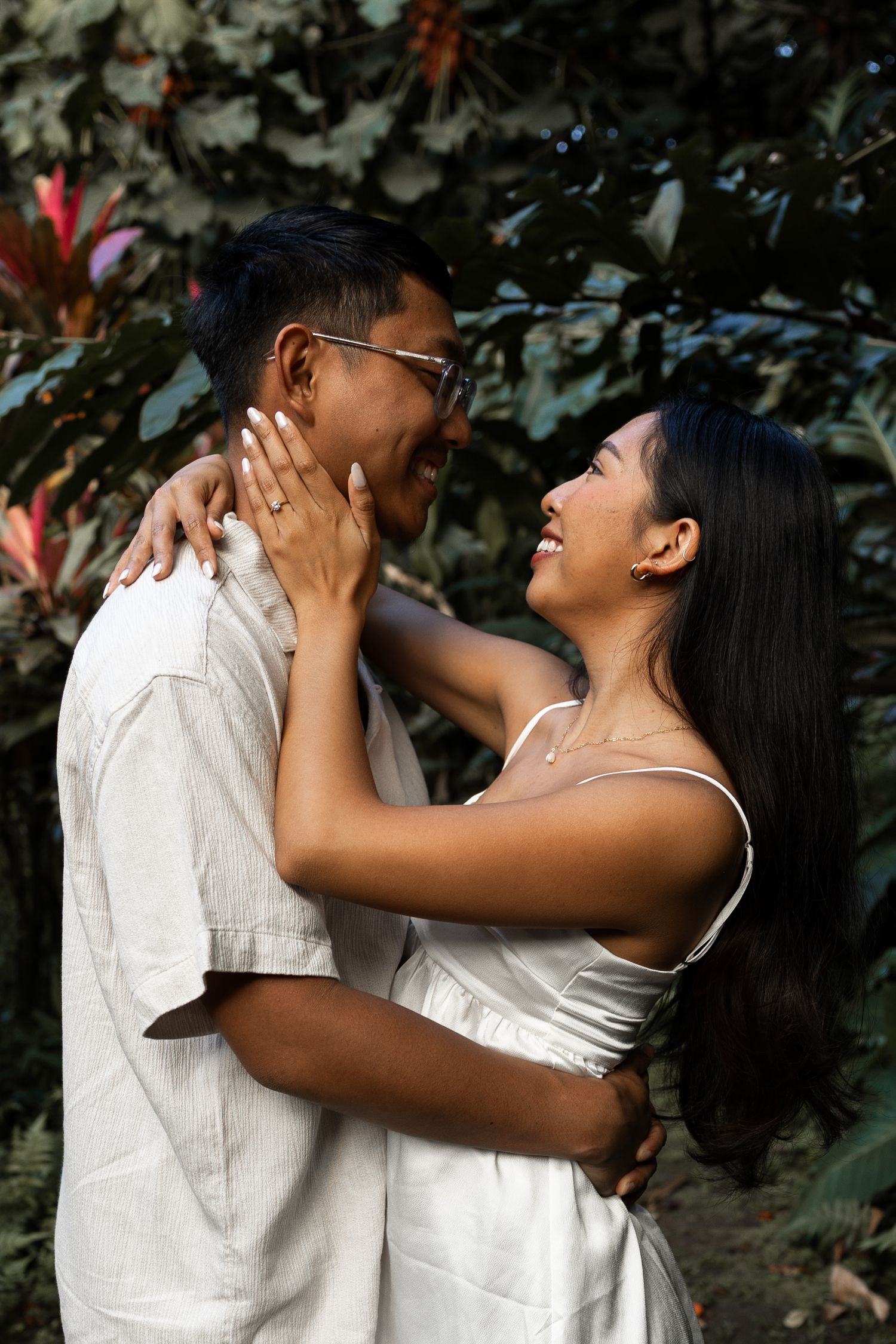 A couple shares a joyful embrace in a lush garden setting.