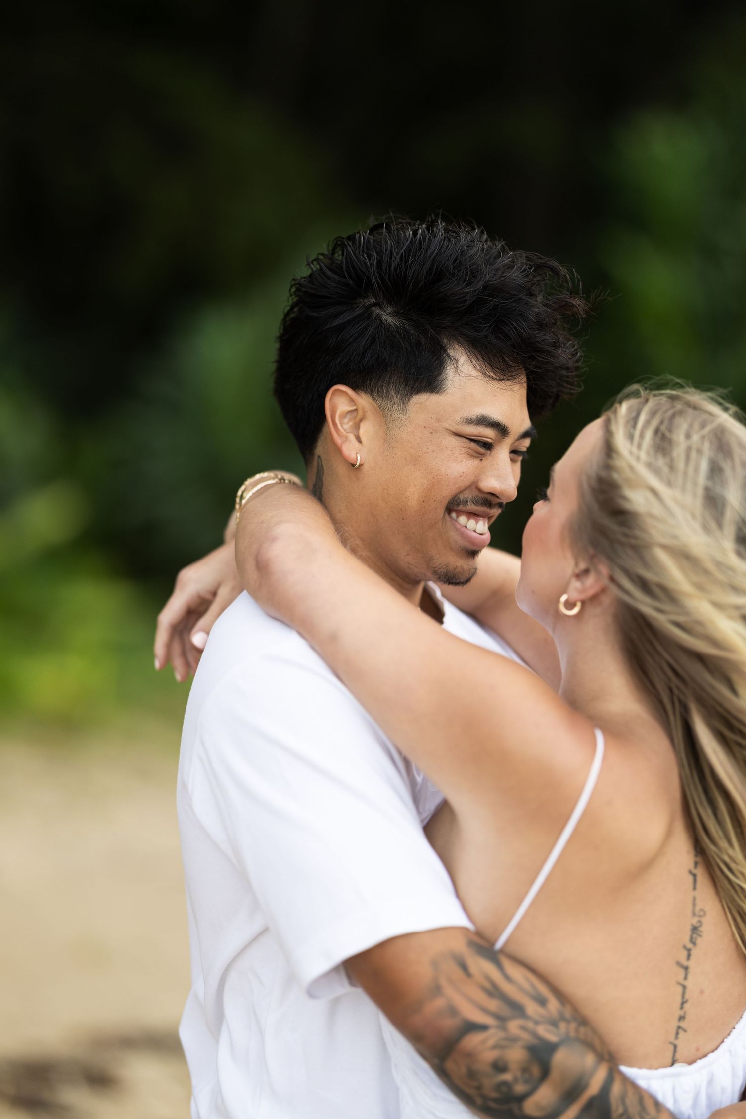 A couple shares an intimate laughing moment on the beach.