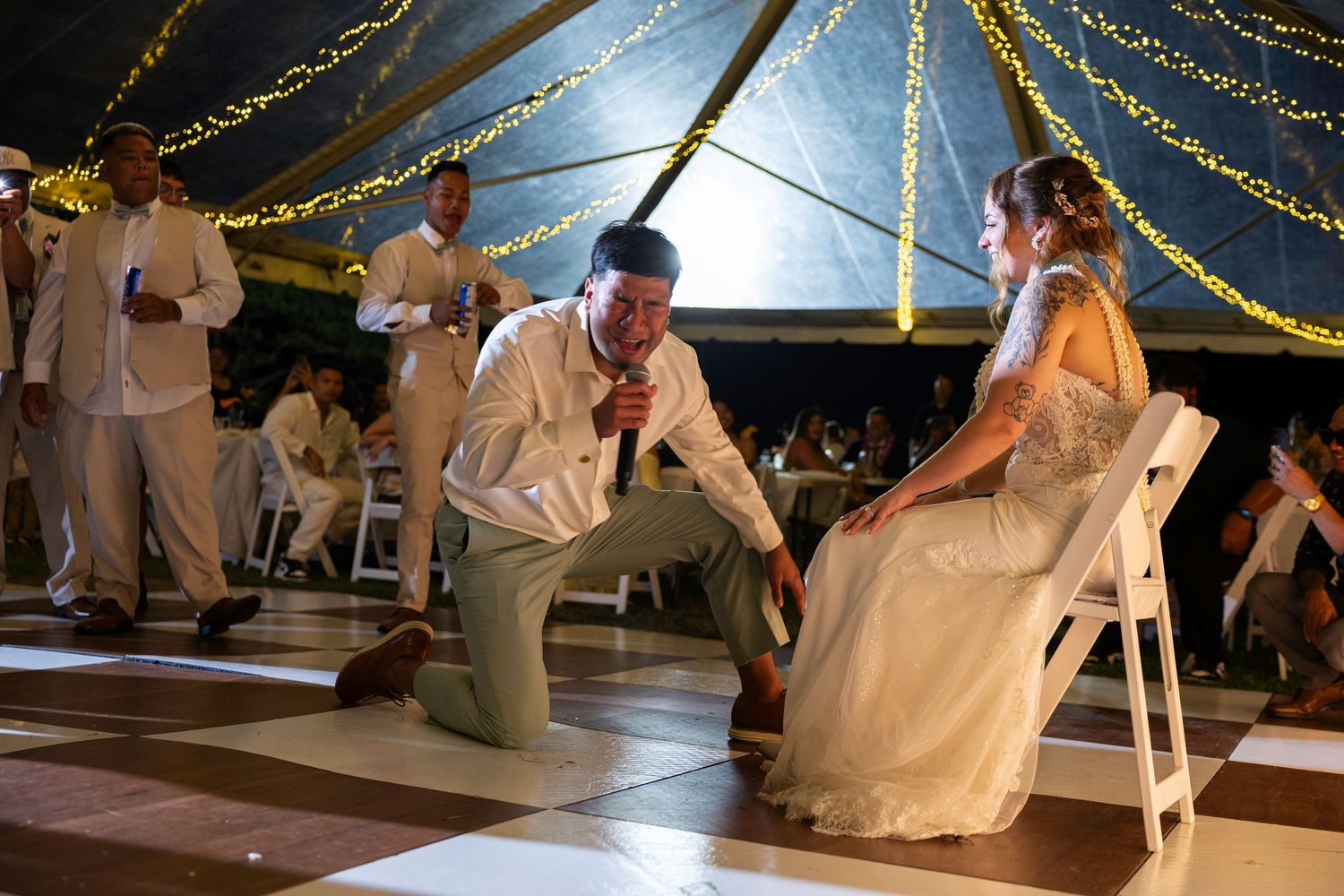 Dancers move gracefully across a wooden dance floor under twinkling string lights at an elegant evening reception.