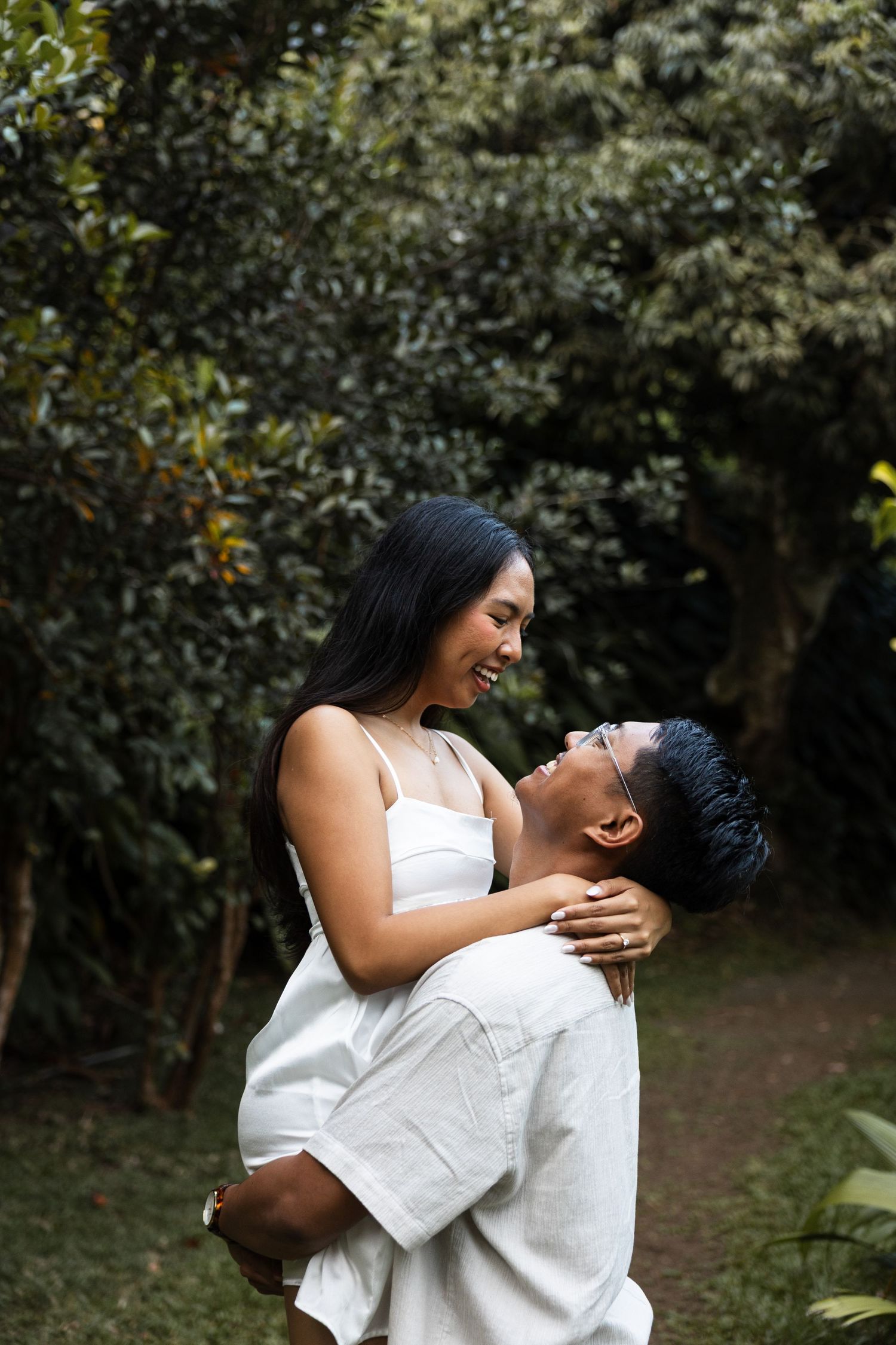 A couple shares a tender moment while embracing in a garden setting.