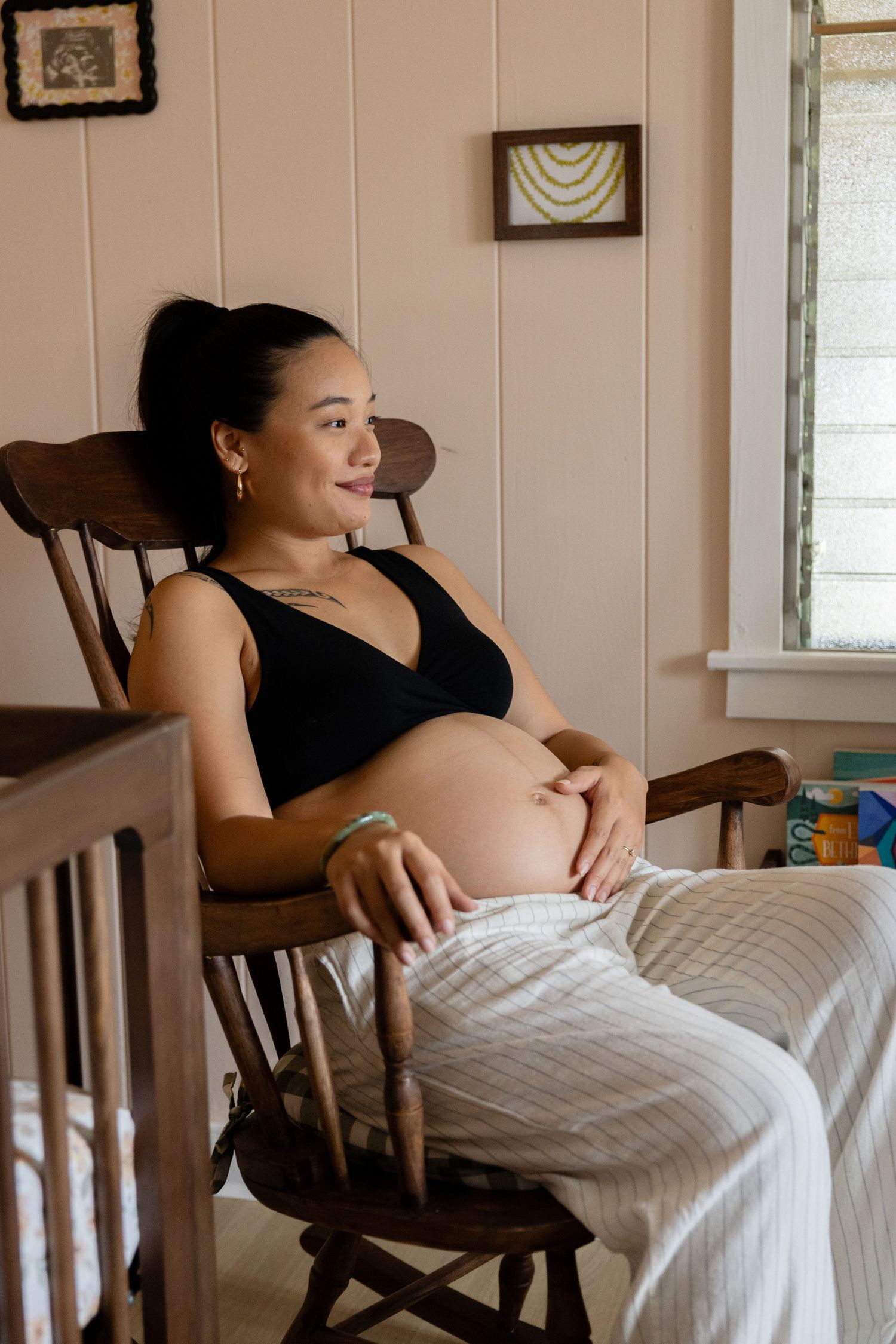 A peaceful maternity portrait in a wooden rocking chair by window light.