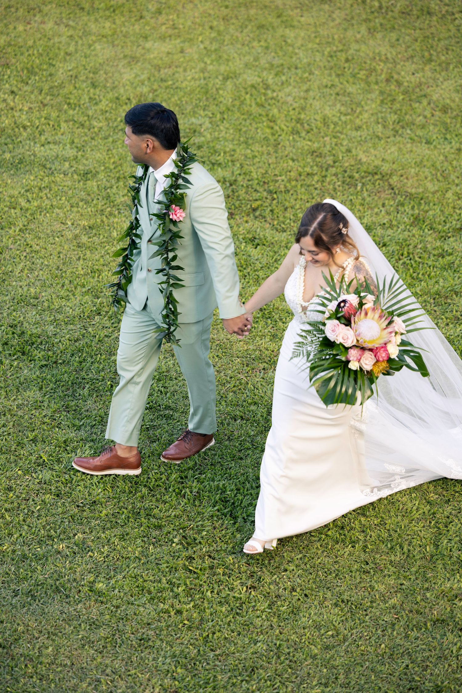 A sequence showing a couple's first look moment on a grassy lawn with tropical flowers and greenery.