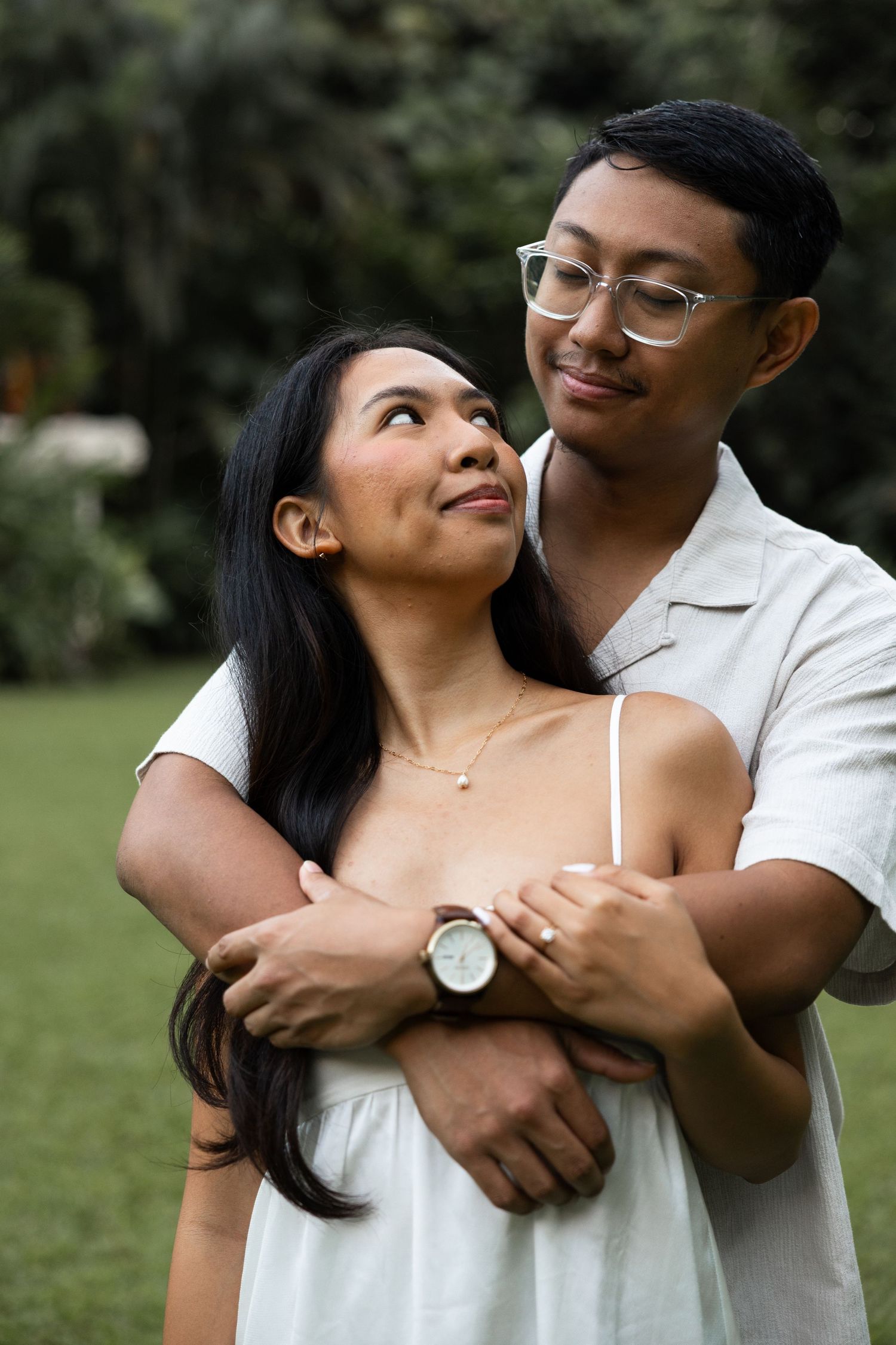 A loving couple embraces while sharing tender glances in a garden setting.