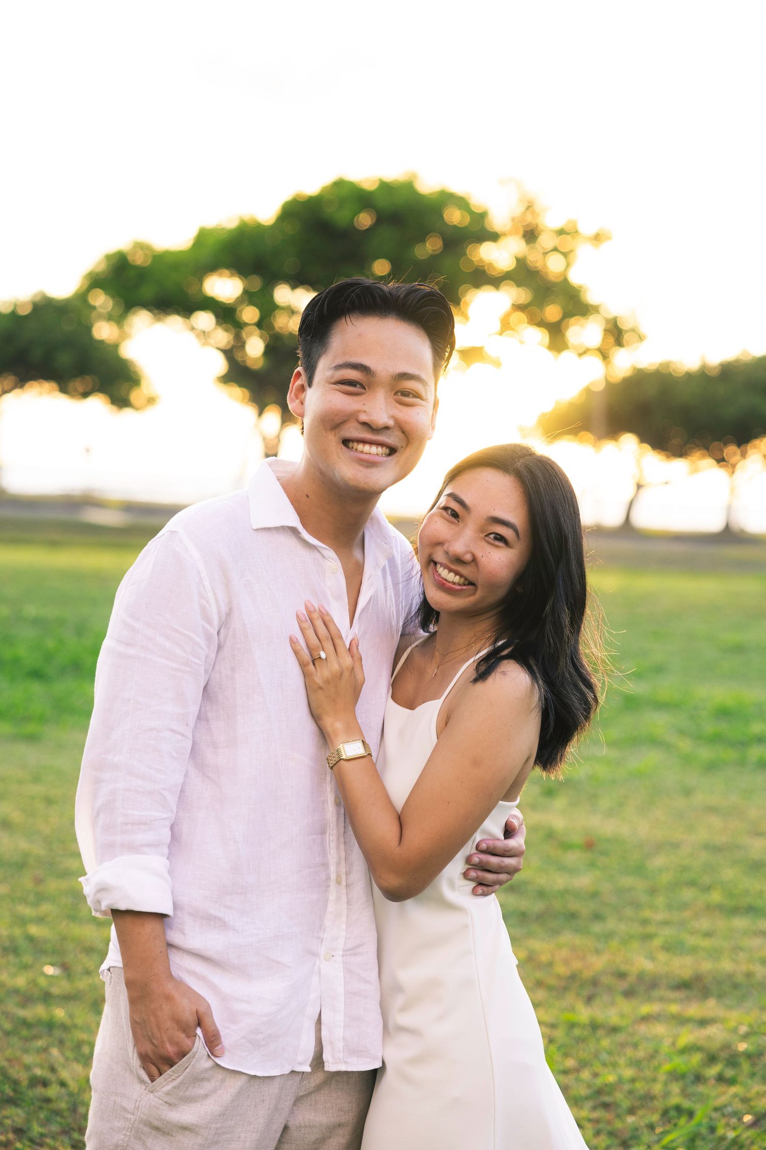 A couple shares joyful moments together in a grassy field during golden hour sunset.