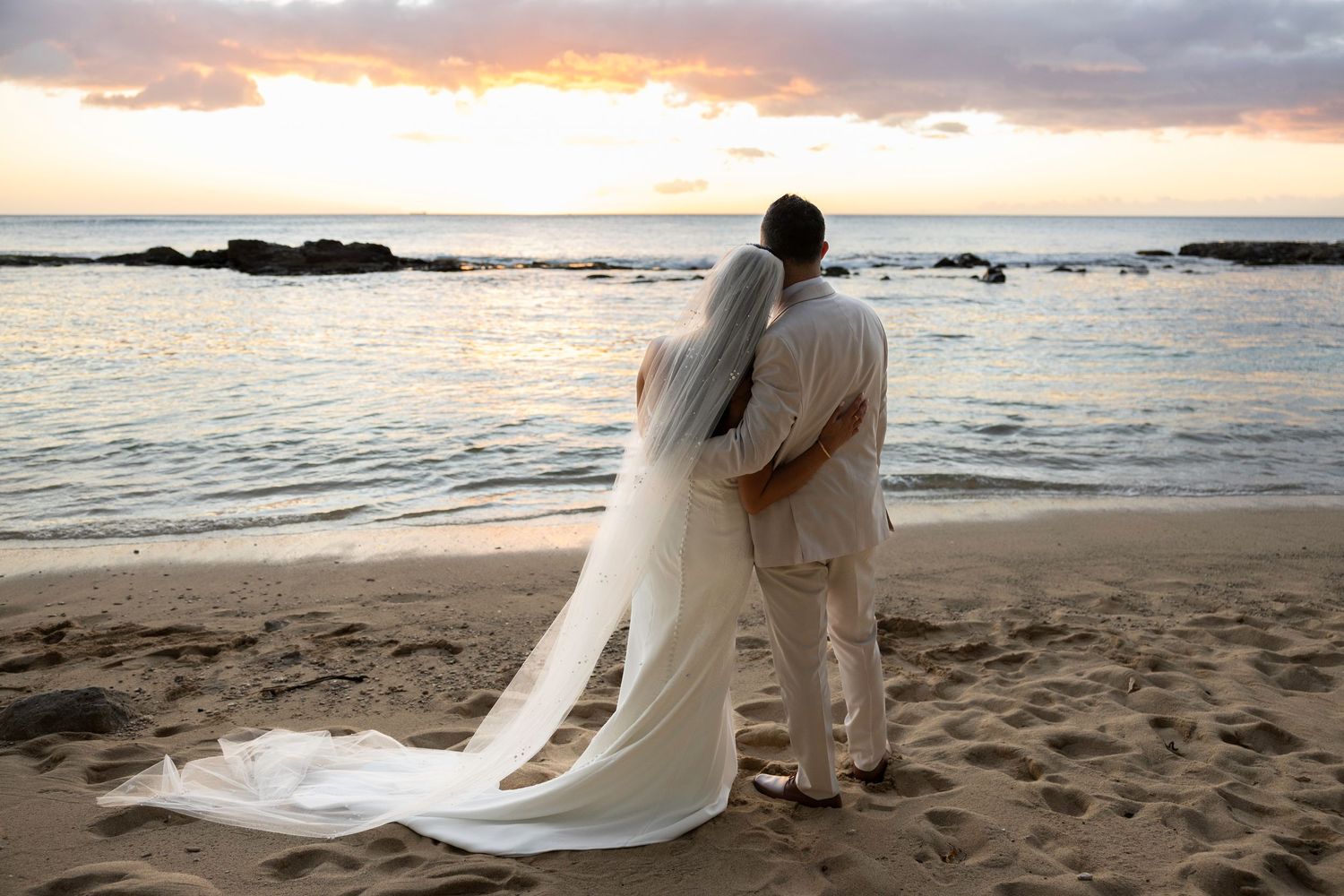A romantic beach wedding photo series at sunset with the couple walking along the sandy shore.