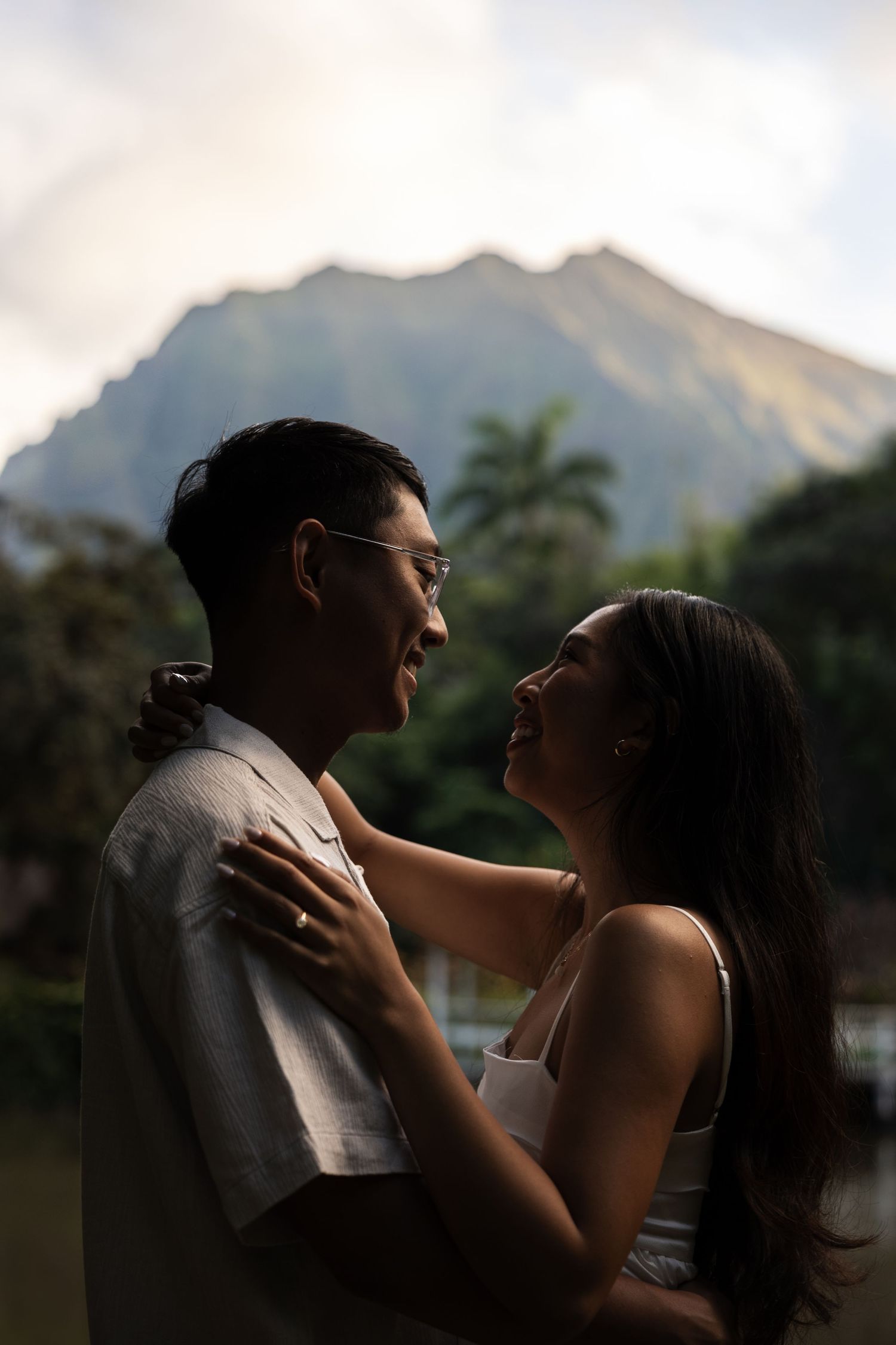 A romantic couple shares an intimate moment with a mountain backdrop at sunset.