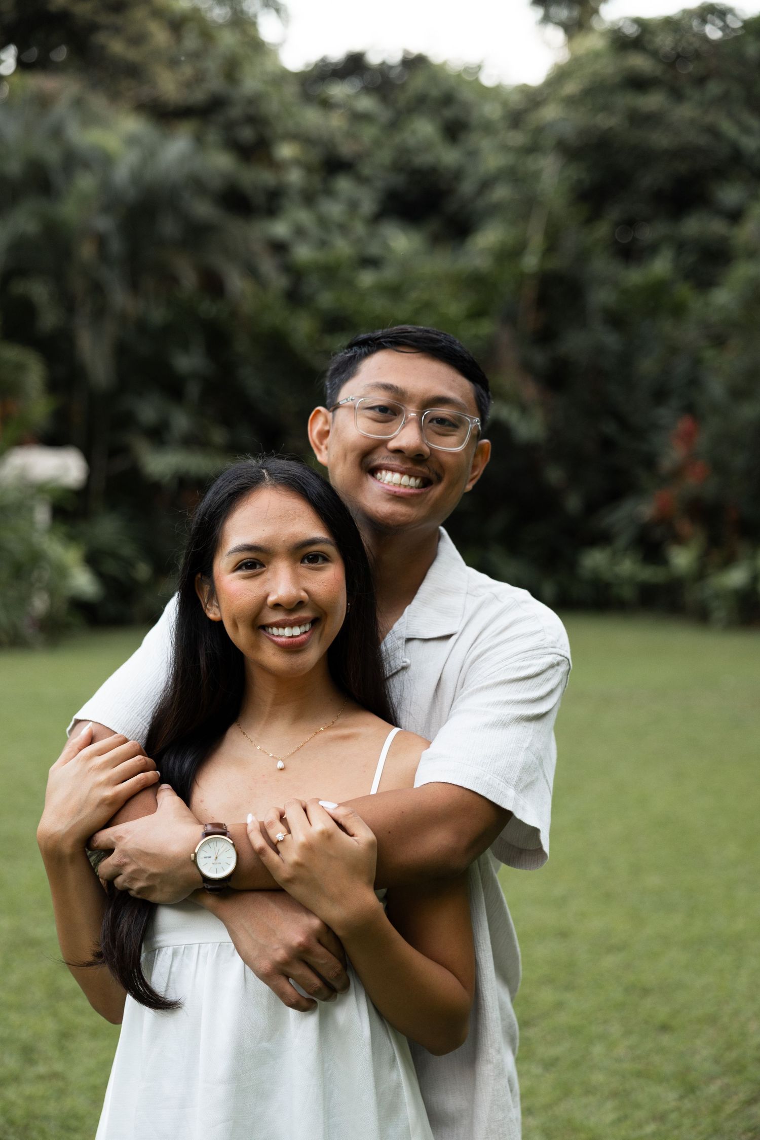 A couple embraces and laughs together in a tropical garden setting.