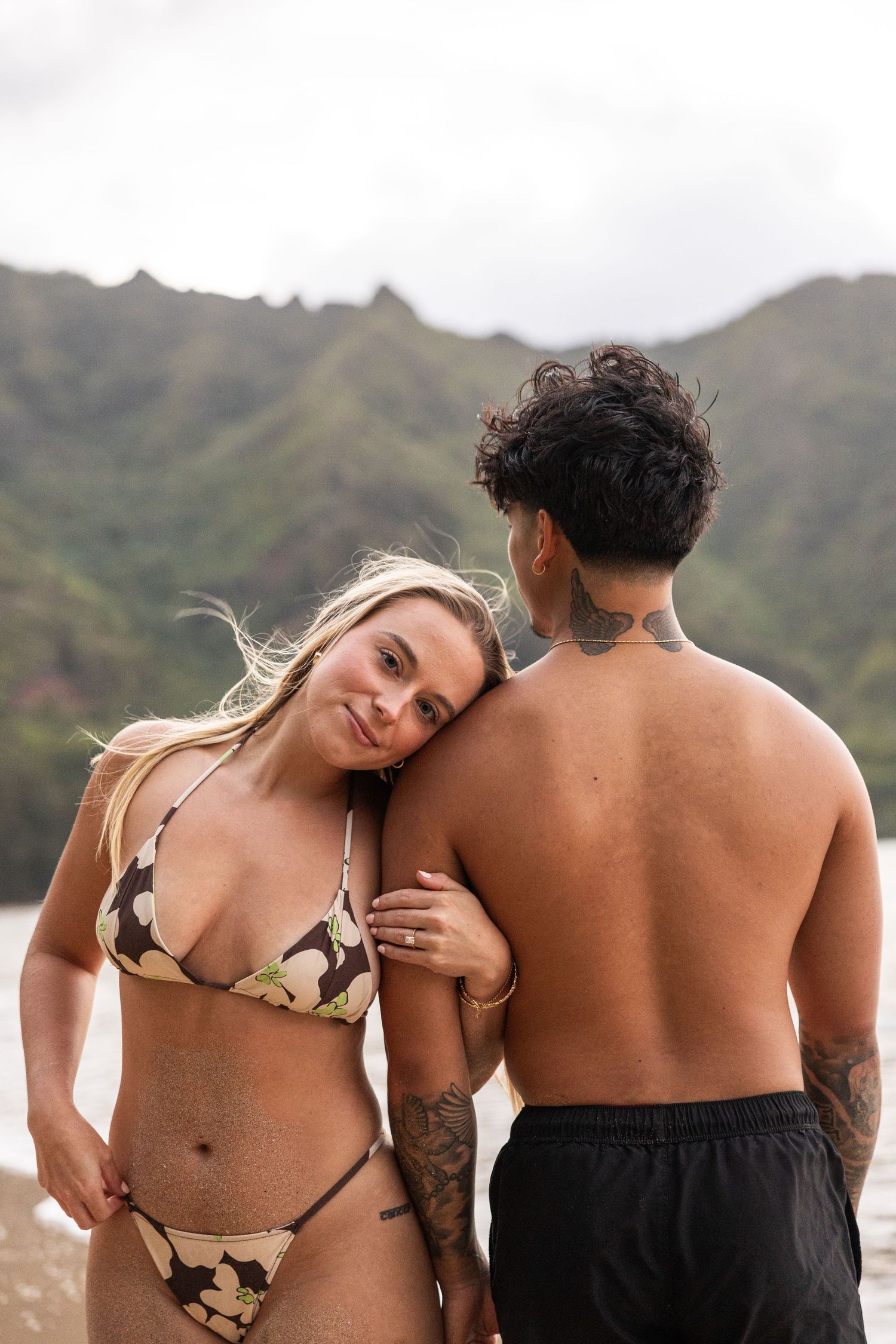 Romantic beach photoshoot with dramatic mountain backdrop in Hawaii.