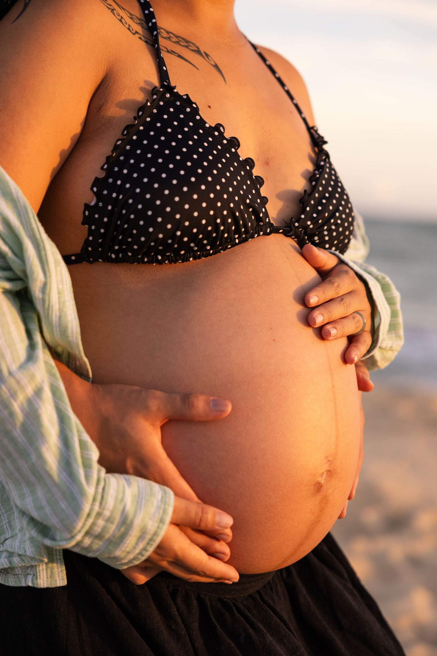 A series of photos showing a pregnant belly in a polka dot bikini top against a sunset beach background.