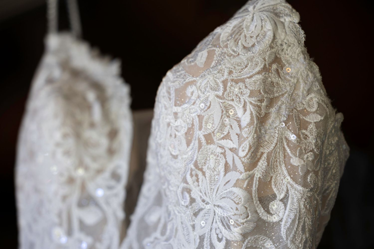 Close-up detail shots of delicate white lace patterns on a wedding dress.