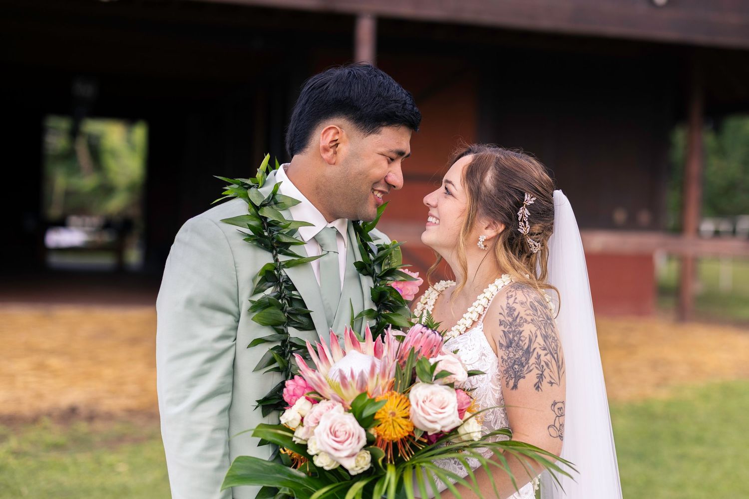 Romantic wedding couple embraces outdoors in a garden setting with pink and orange floral bouquet details.