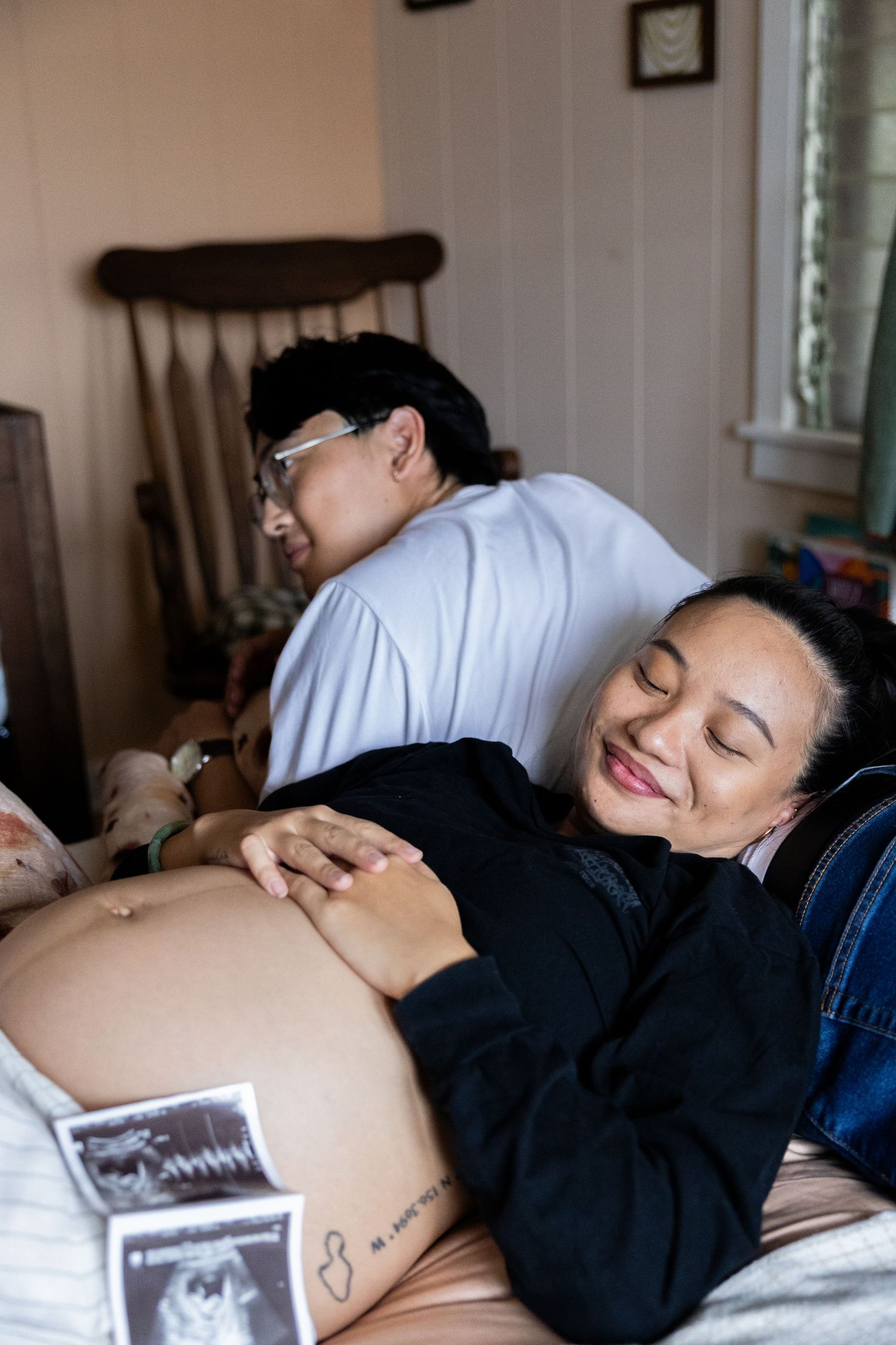 A relaxing maternity scene in a bedroom with ultrasound photos visible.