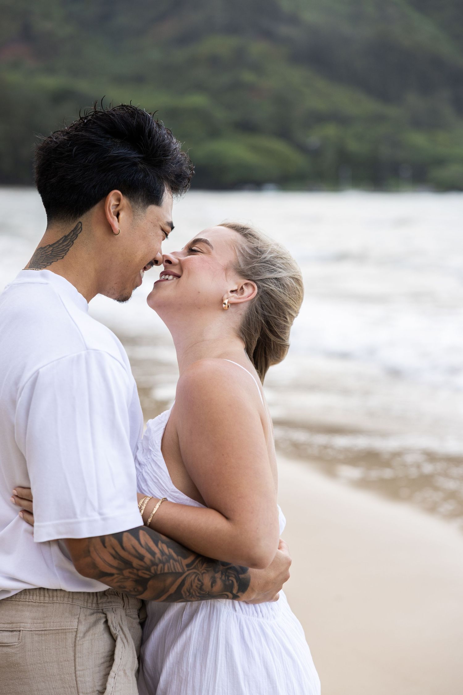A couple shares a romantic moment while embracing on a tropical beach.