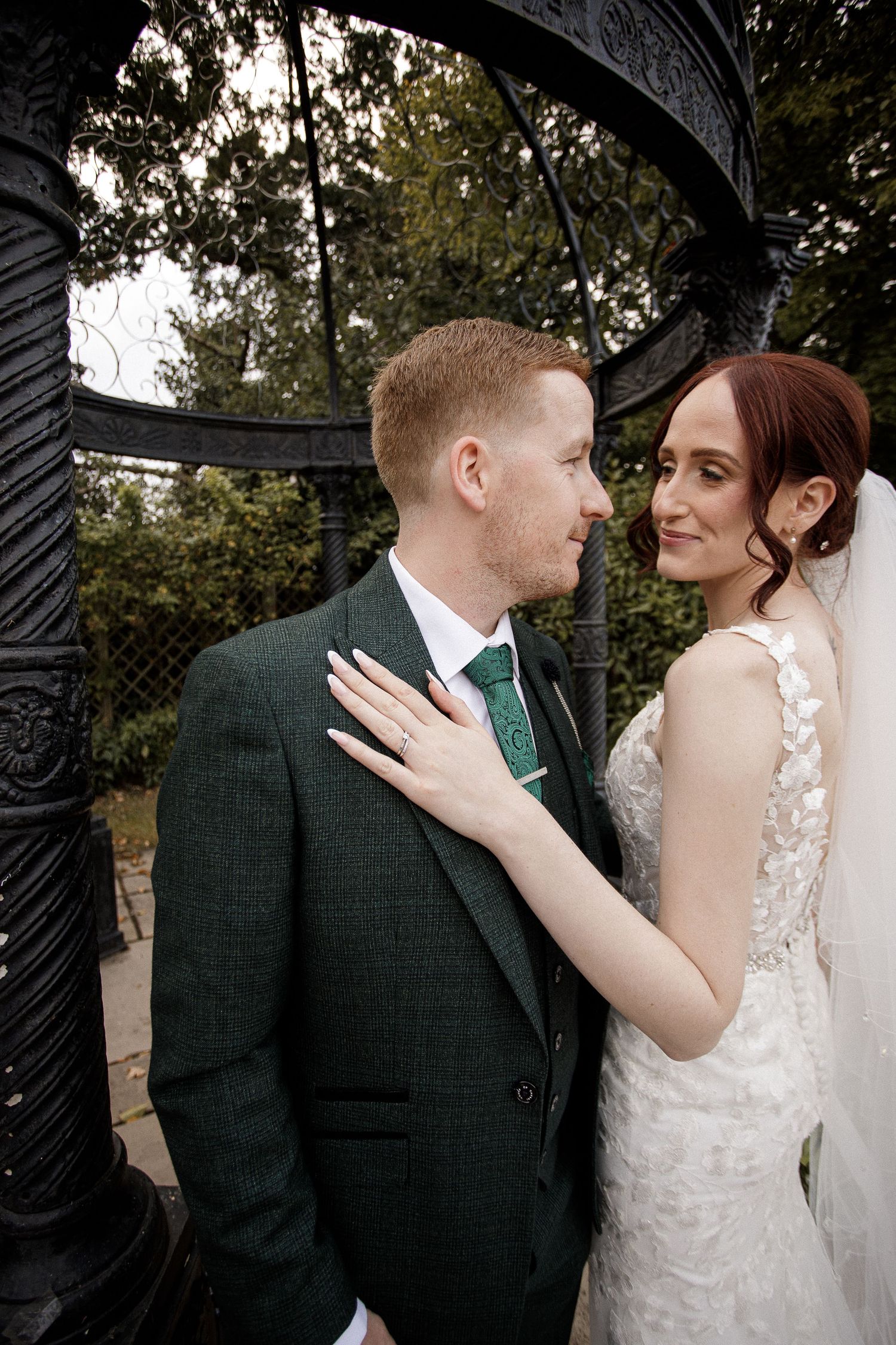 Romantic wedding portraits captured under an ornate black metal archway.