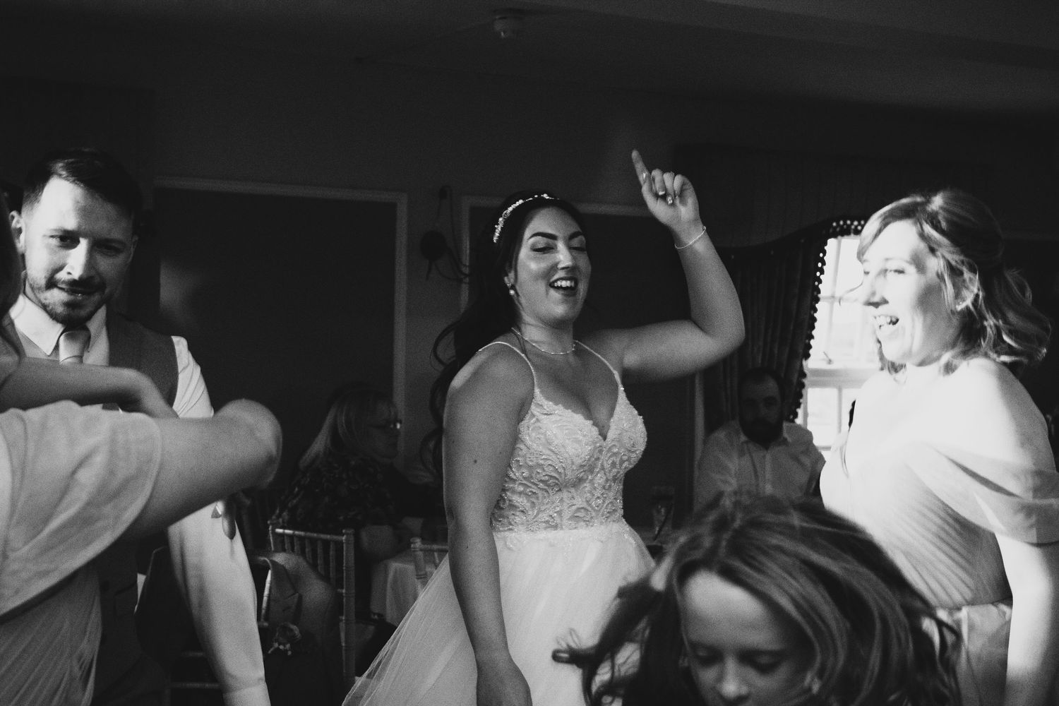 Candid black and white shot of wedding reception dance floor celebration.