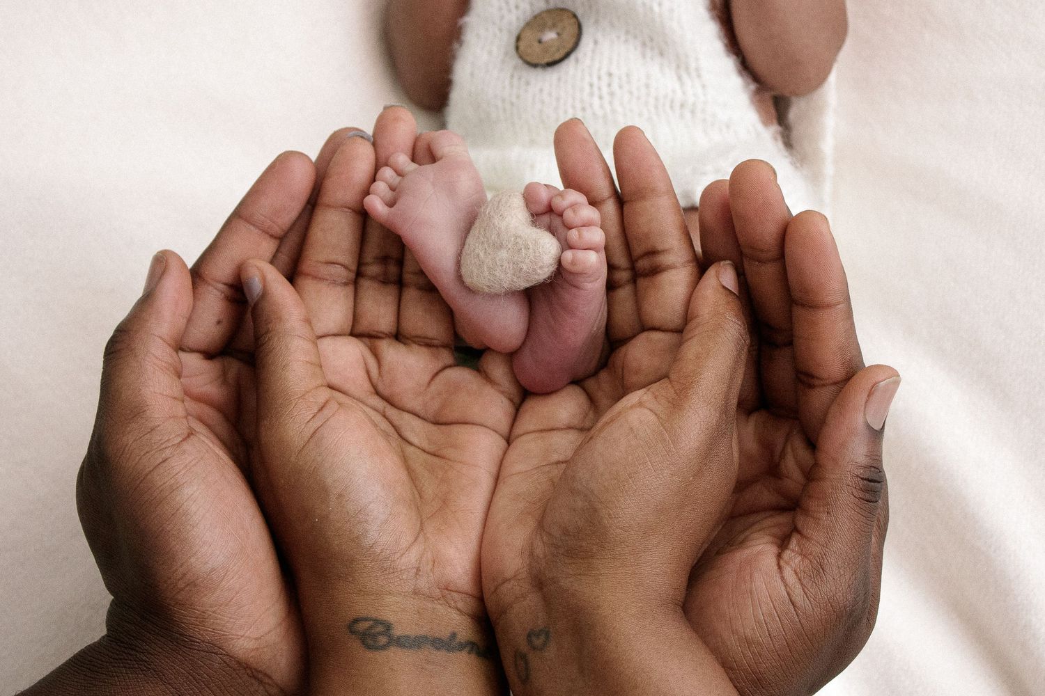 Series of hands gently cradling a baby against white background.