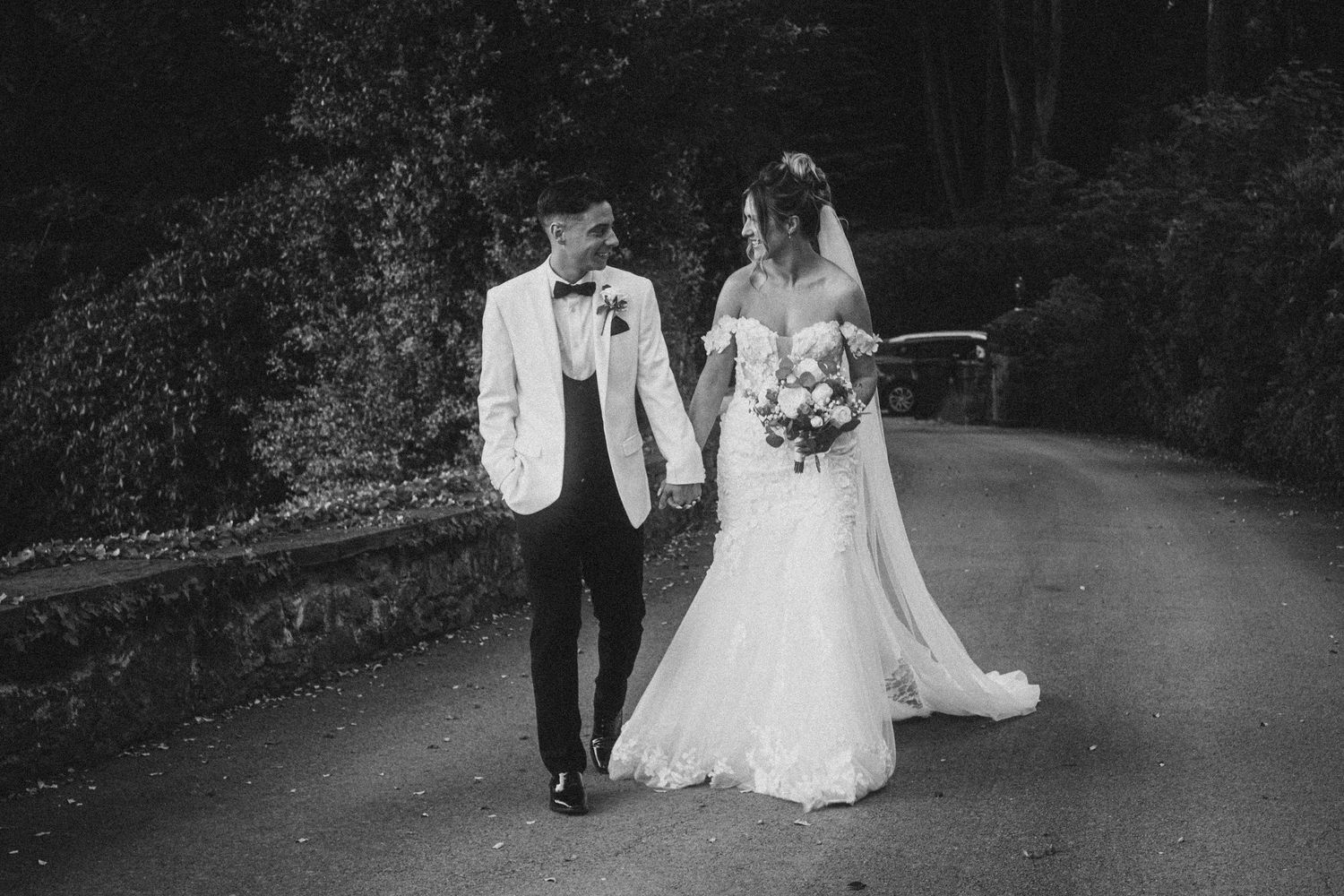 Artistic black and white wedding photos capturing romantic moments on a garden walkway.