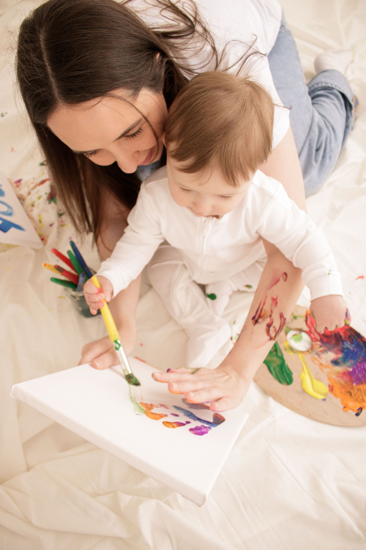 Overhead view of painting activity with vibrant colors on white paper.