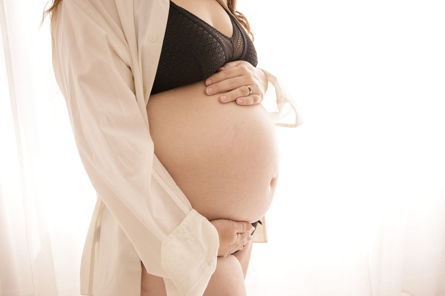 Intimate maternity photography with soft white fabric draping.
