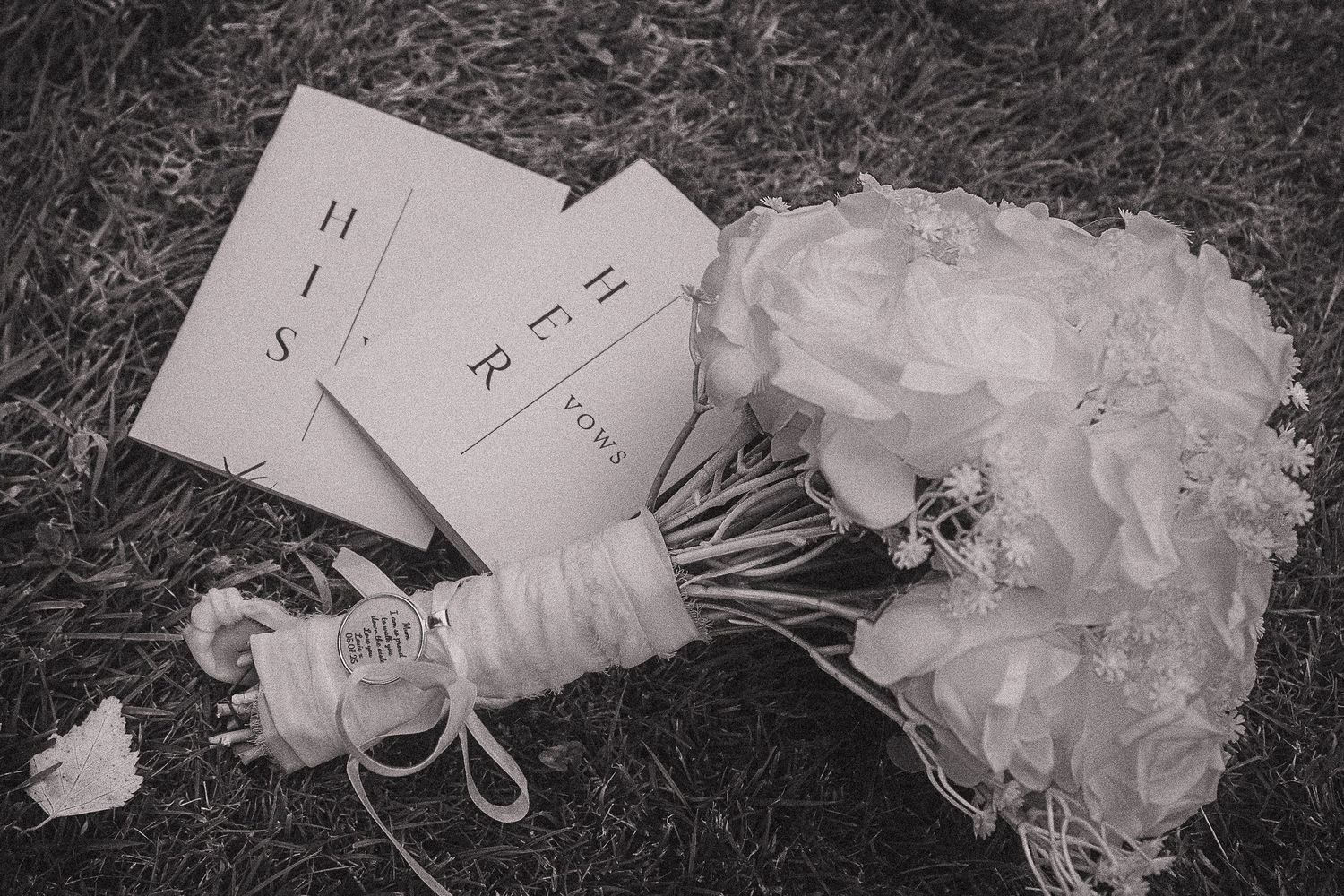 Wedding garter details laid out on grass in black and white photography.