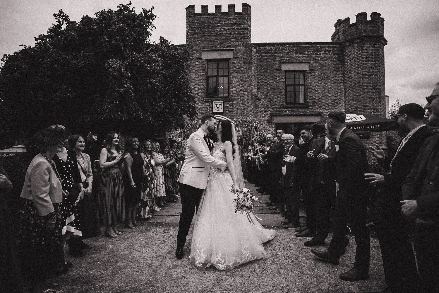 Wedding celebration outside a historic castle with stone walls and battlements.