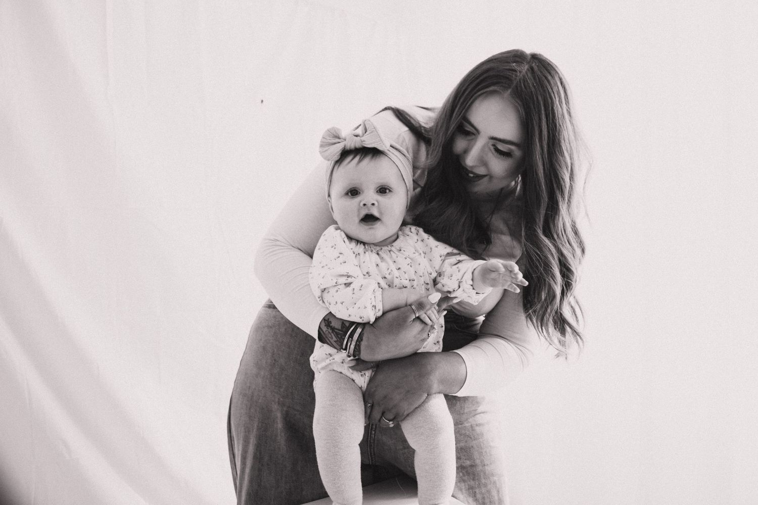 A black and white photo series showing tender moments between a parent and baby in various candid poses.