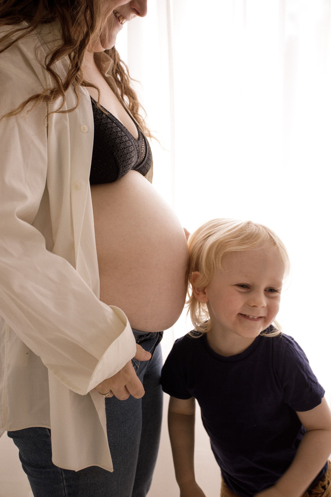 Candid maternity photos capturing joyful interaction between mother and child.
