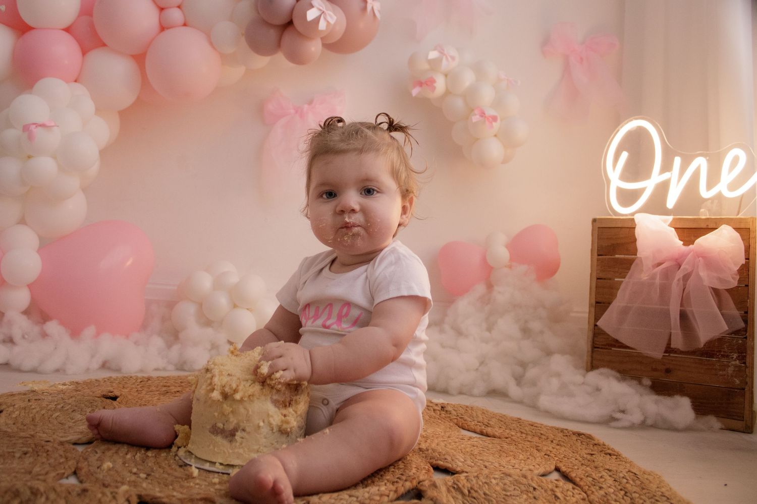 First birthday photoshoot setup with pink balloons, decorations and tulle dress display.