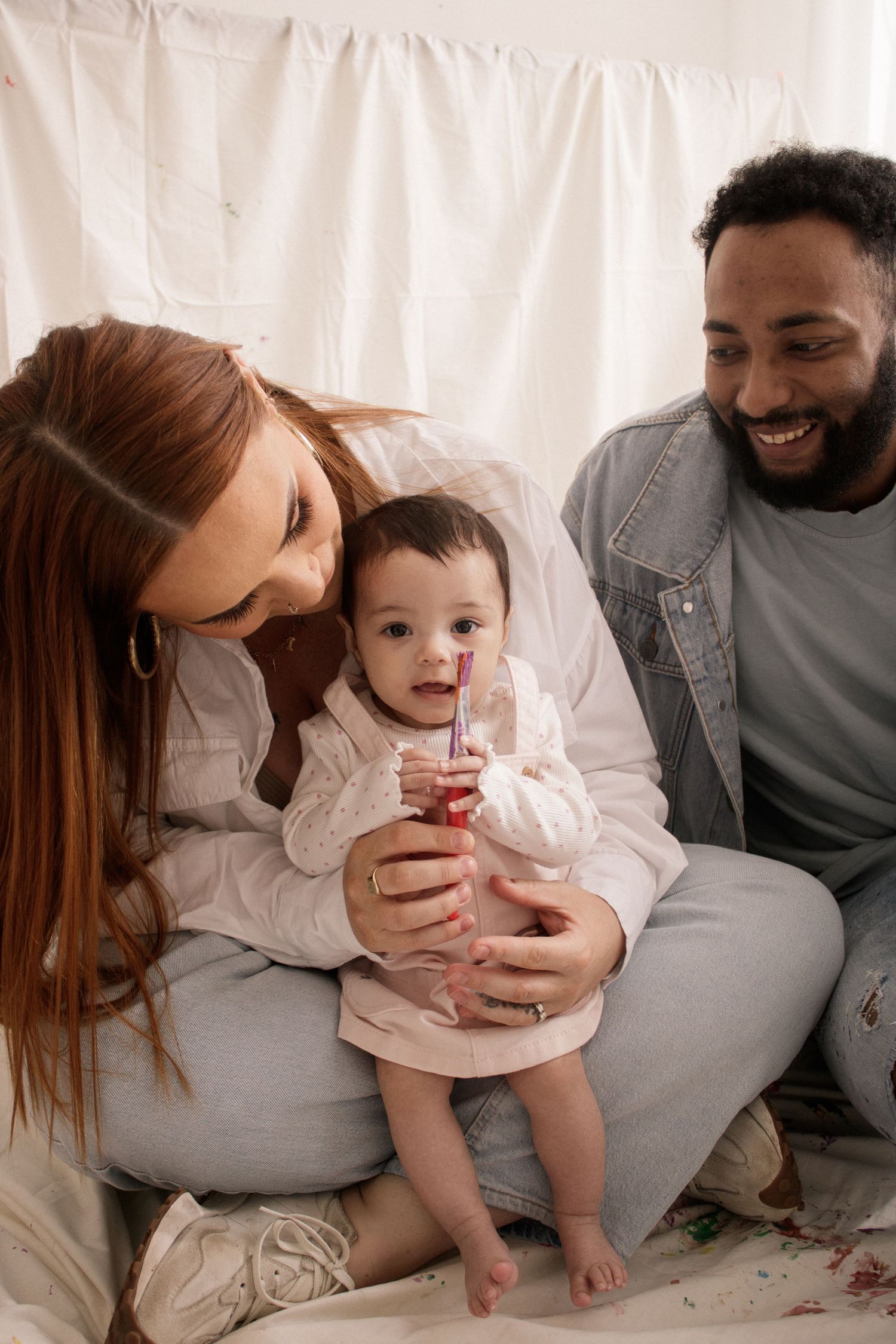 Family sharing intimate moment together on white backdrop.