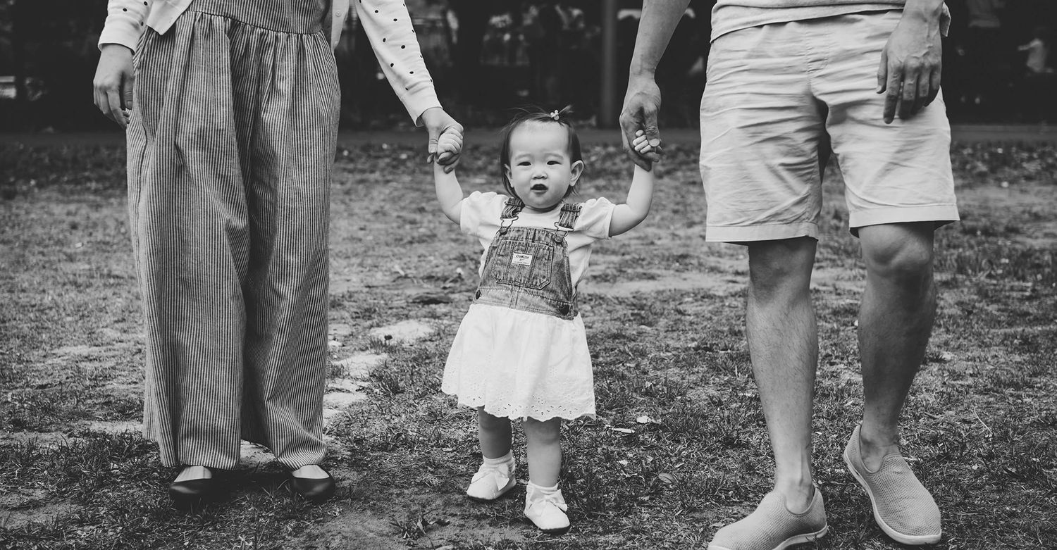 Close up of baby girl walking while holding her parent's hands during outdoor family session - Zara King Photography, Sydney Australia