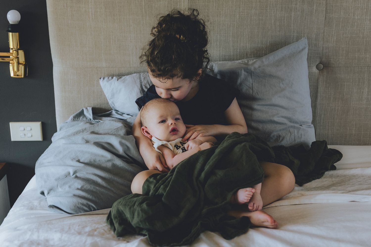 Sister kissing newborn brother's forehead during family photo session - Zara King Photography, Sydney Australia
