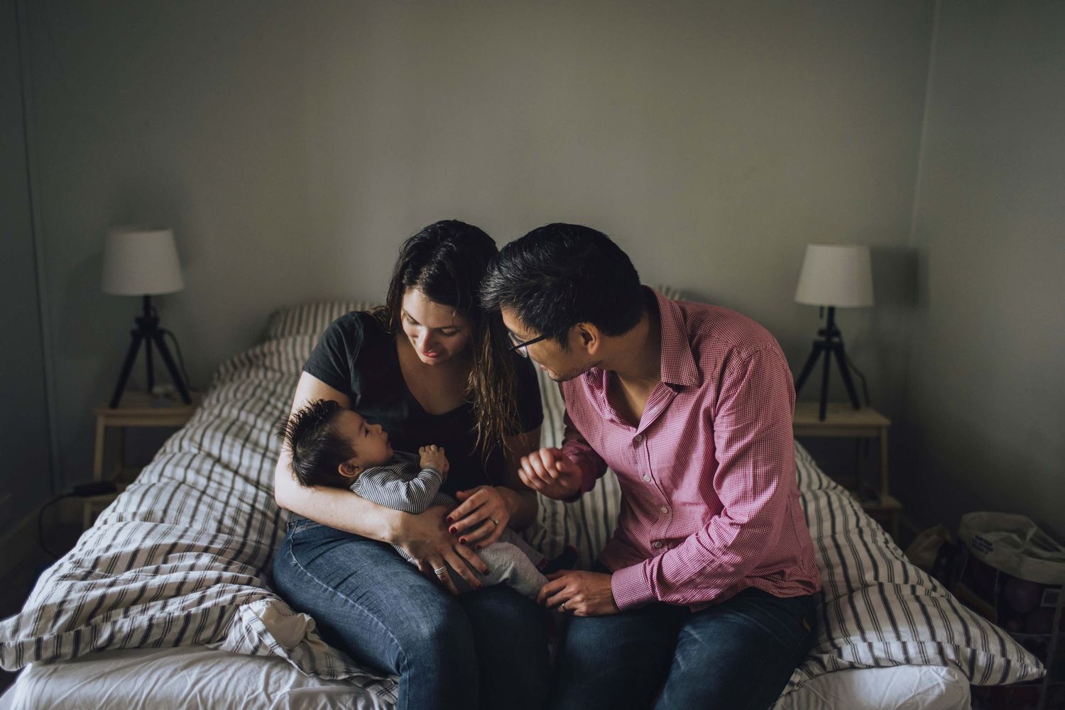 Candid portrait of parents playing with newborn baby during in-home session - Zara King Photography, Sydney Australia