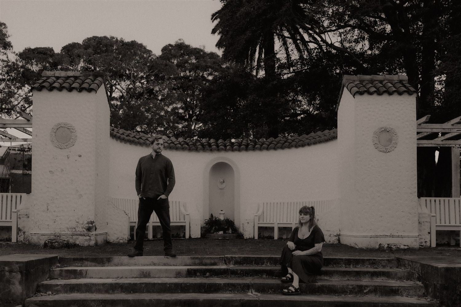 Zara King and fiancé, he's standing and she's sitting on steps in front of an altar