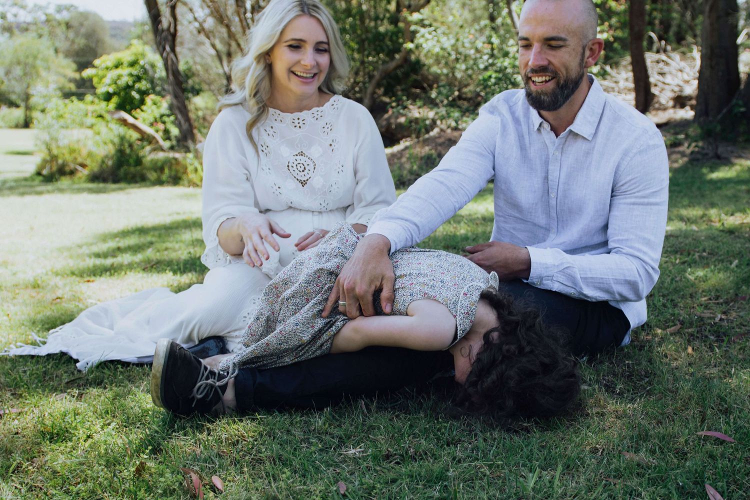 Mum and dad ticking toddler daughter in their backyard during at-home session - Zara King Photography, Sydney Australia