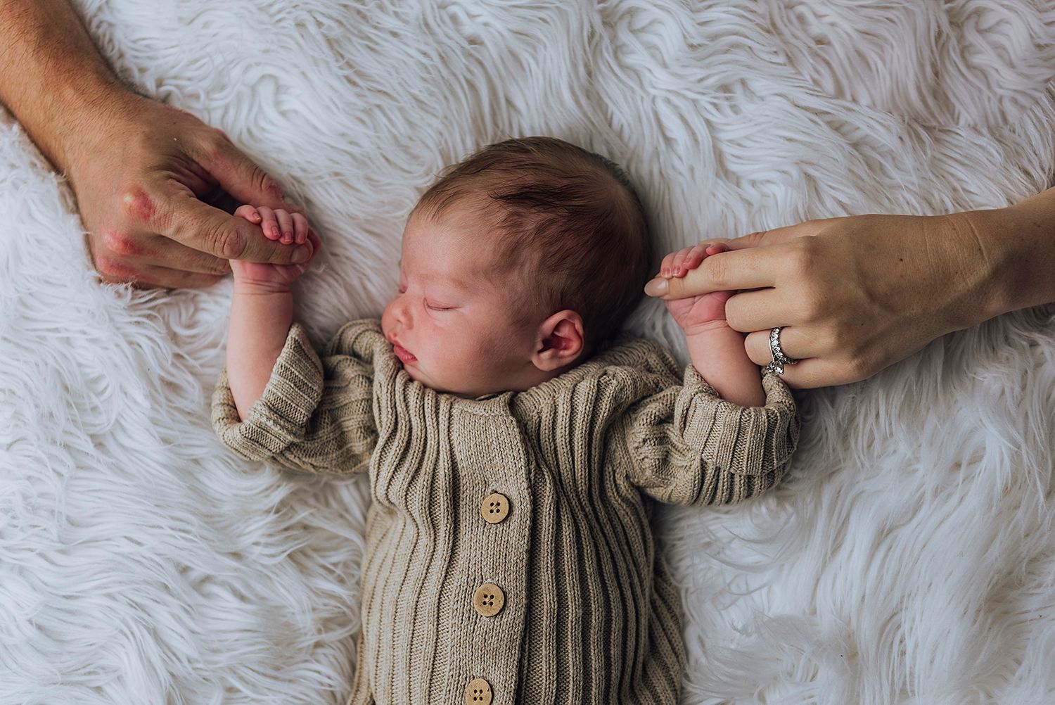 Newborn baby asleep on her back while she's holding both of her parents index fingers - Zara King Photography, Sydney Australia